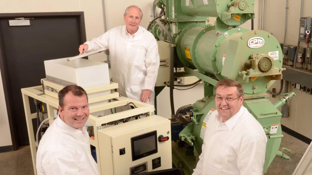three scientist surrounding a pellet machine