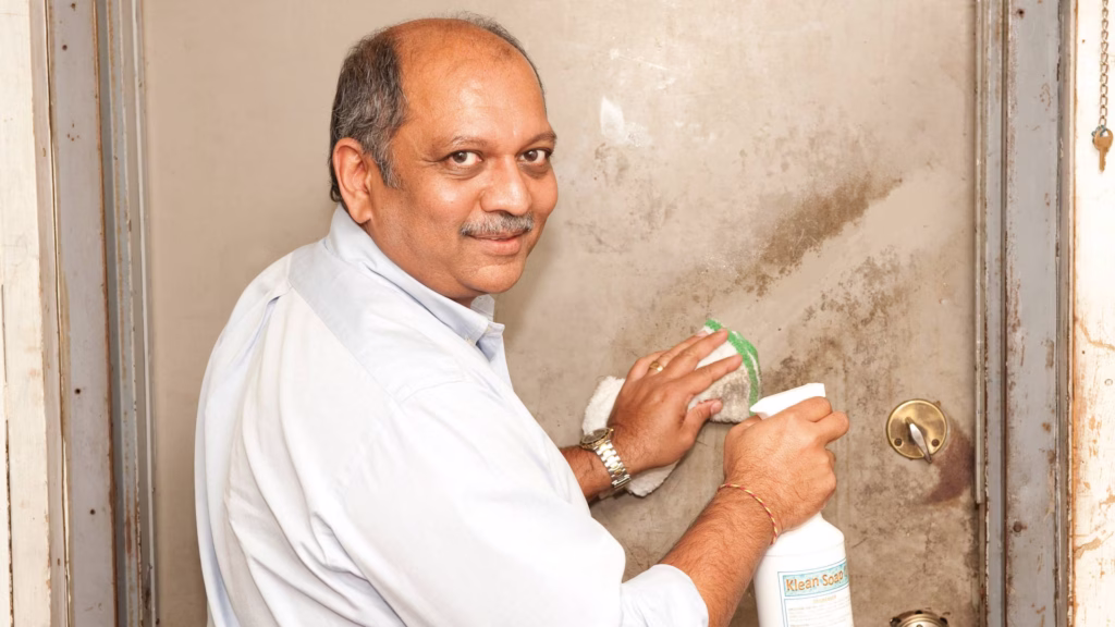 balding man wiping away grease with cloth on a door