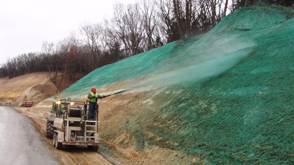 truck spraying green binder on grass by the side of the highway